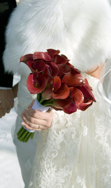 זר פרחים אדומים על רקע שמלת כלה לבנה